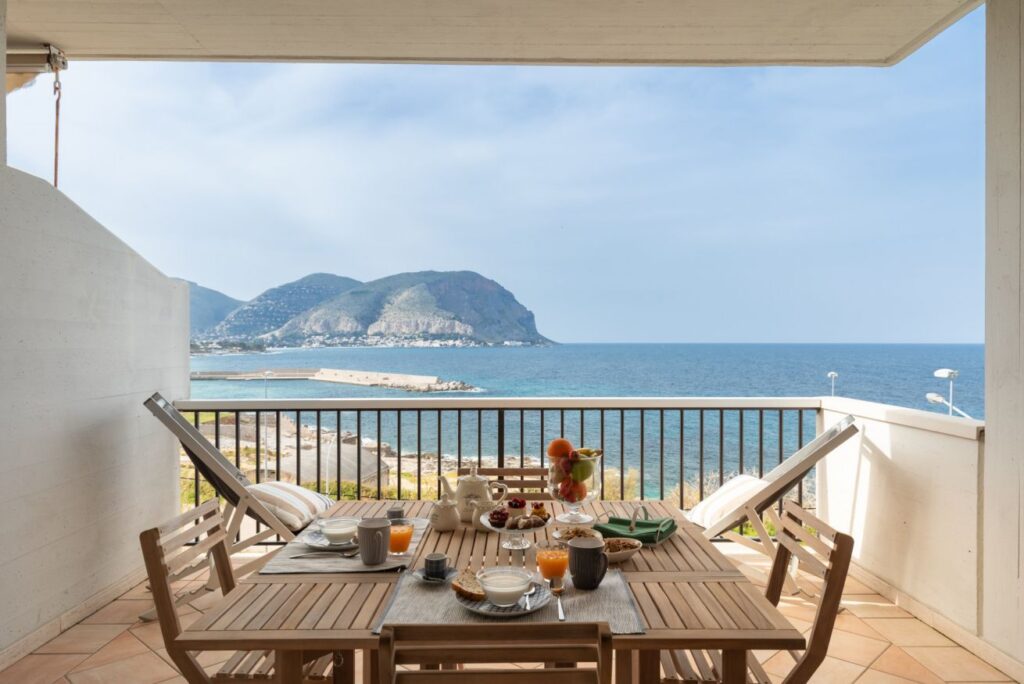 Breakfast table set on a sunny private terrace with sea and mountain views in Mondello Bay