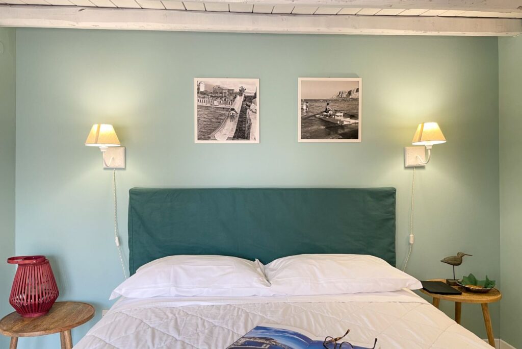 Elegant boutique hotel bedroom interior design with custom teal headboard and coastal decor at Mondello Bay