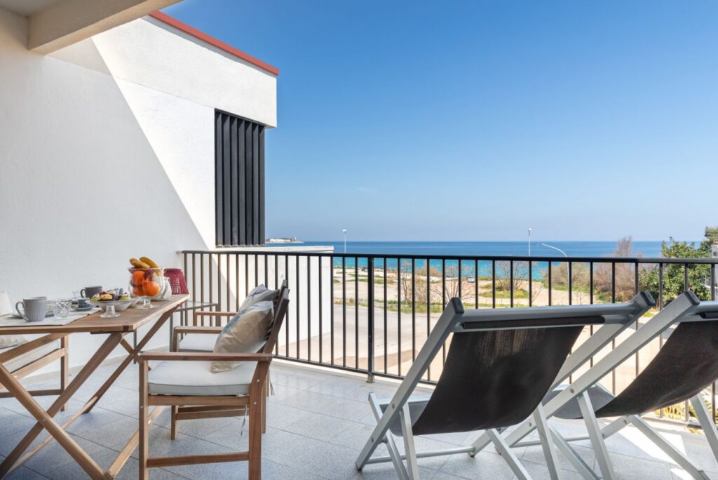 Cozy balcony seating with seaside cushions and breakfast table facing the open blue sea