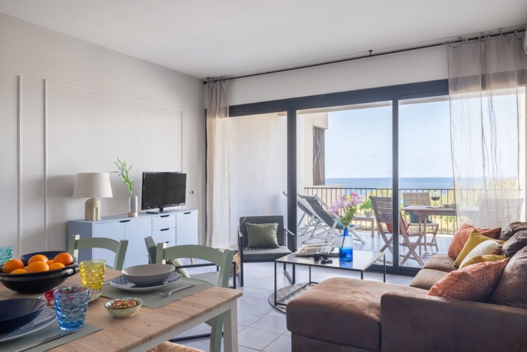 Modern open-plan living and dining area with sliding glass doors leading to a sea view terrace
