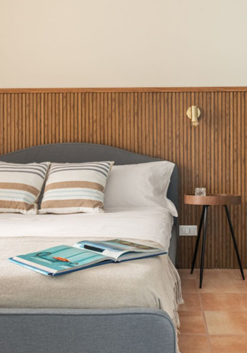 Cozy bedroom detail in a Mondello holiday home featuring a wooden slatted headboard and modern nightstand